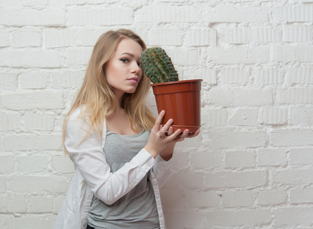 girl with cactus in the pot at the white wallsの写真素材