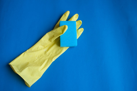 Rubber glove for cleaning with a sponge on a blue background
