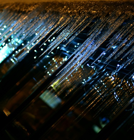 Small blueish lights behind icicles reflected a windowの写真素材