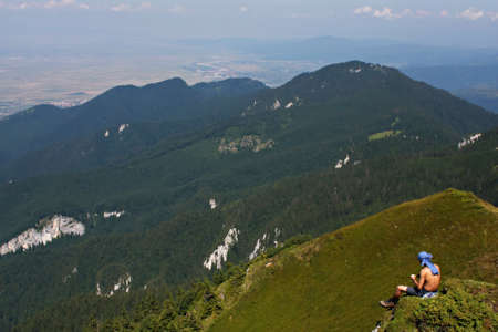 A man having a lunch brake on the top of a mountainの写真素材