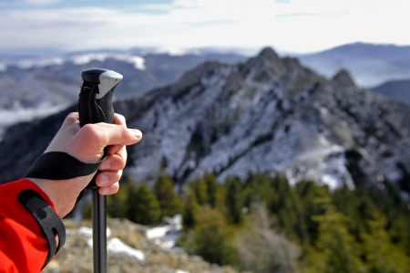 Hand of a man holding a hiking pole on top of a mountainの写真素材