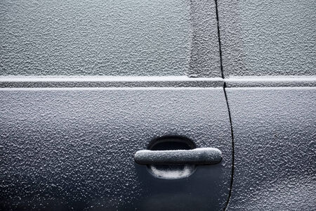 Car door covered with thin layer of fresh snowの写真素材