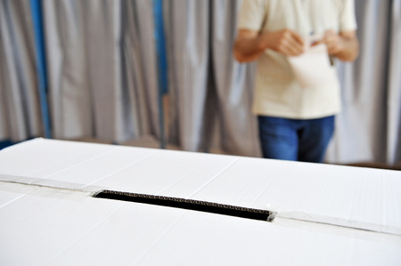 Closeup with a ballot box and a man comming out from the vote cabin in the backgroundの写真素材