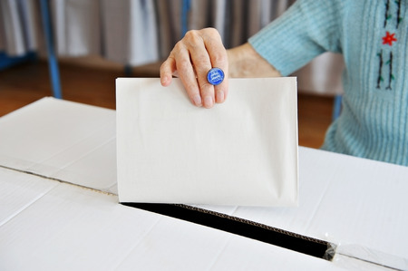 Close up of a woman's hand putting her vote in the ballot boxの写真素材