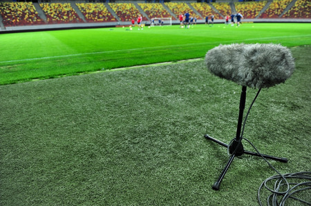 Professional sport microphone on a football field with players training in the backgroundの写真素材
