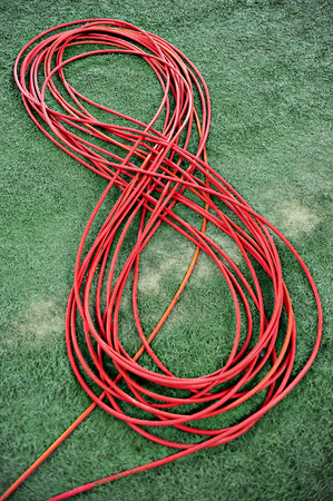 Television red cable coiled on artificial turf
