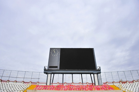 Football scoreboard with clock and empty tribune with overcast sky on backgroundの写真素材