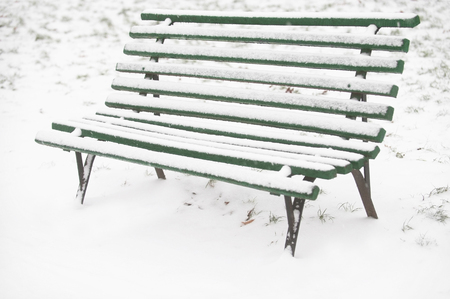Fresh snow on a green wooden bench in a parkの写真素材