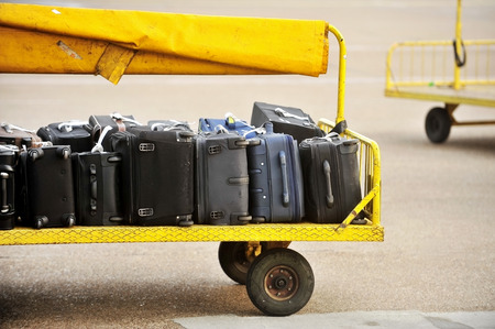 Yellow trolley loaded with luggage on an airport tarmac trackの写真素材