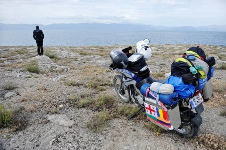 SEVAN, ARMENIA - JULY 5: Adventure motorcycle loaded with luggage and motorcyclist on the shore of Sevan Lake, on July 5, 2014 in Armenia. Sevan Lake is one of the largest freshwater high-altitude lakes in the world.のeditorial素材