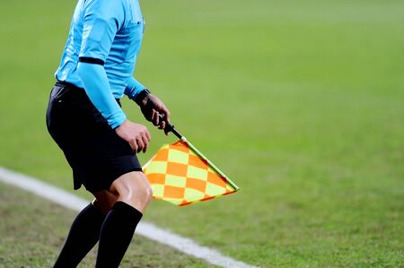 Assistant referees signaling with the flag on the sideline during a soccer matchの写真素材