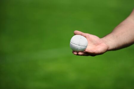 Hand holding a rounders ball. Rounders is a bat and ball game between two team that involves hitting a hard leather cased ball with a wooden bat.の写真素材