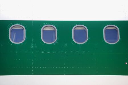 Airplane windows in a row on a green fuselageの写真素材
