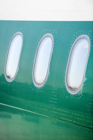 Airplane windows in a row on a green fuselageの写真素材