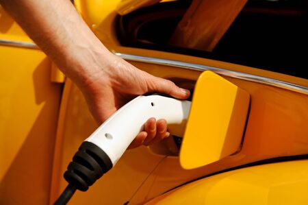 Hand holding an electric plug in for charging electric carの写真素材
