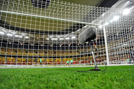 Big and furry sport microphone on a soccer field behind the goal netの写真素材