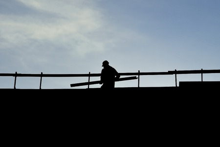 Construction worker silhouette on a construction with blue sky on backgroundの写真素材