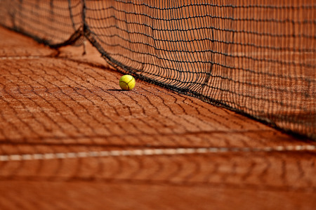Detail shot with a tennis ball close to the net on a tennis clay courtの写真素材