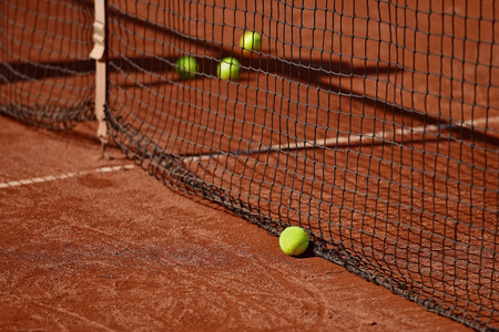 Detail shot with tennis balls close to the net on a tennis clay courtの写真素材