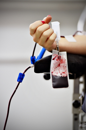 Detail with the hand of a blood donor and a plastic blood bag in a hospitalの写真素材