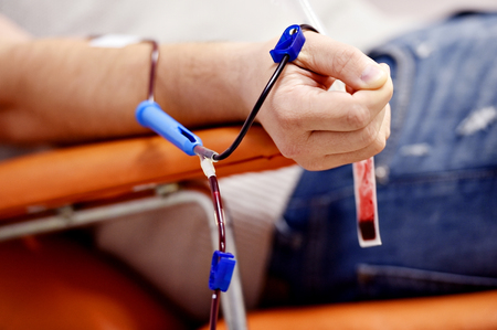 Detail with the hand of a blood donor and a plastic blood bag in a hospitalの写真素材