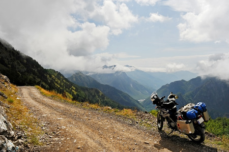 THETH, ALBANIA - AUGUST 22: Adventure motorcycle loaded with luggage on a dirt road with beautiful mountain landscape in background on August 22, 2015 in northern Albania.のeditorial素材