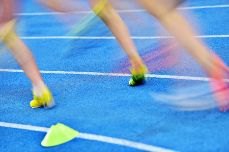 Blurred athletes by a slow camera shutter speed are competing on blue sprint trackの写真素材