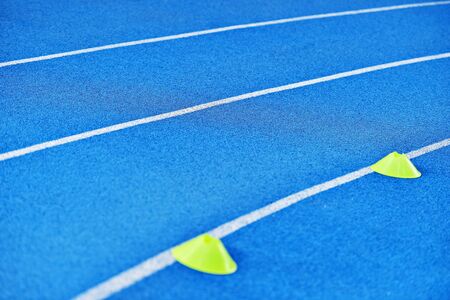 Athletics blue sprint track with yellow marker training conesの写真素材