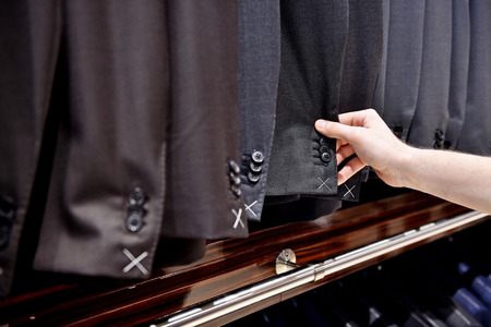 Detail shot with hand picking out man suit jacket in a suit shopの写真素材