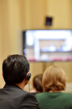 Unrecognizable people using in ear headphones for translation during event