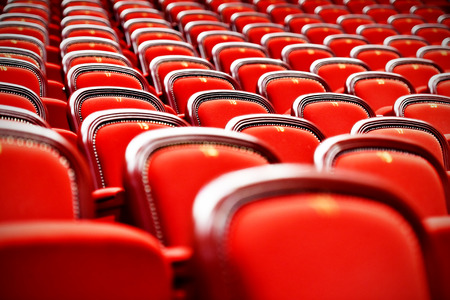 Rows of empty red velvet seats inside a theaterの写真素材