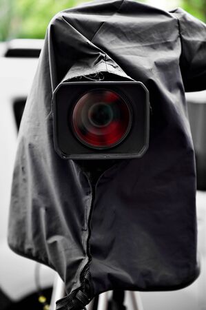 News camera on a tripod protected by a black rain cover