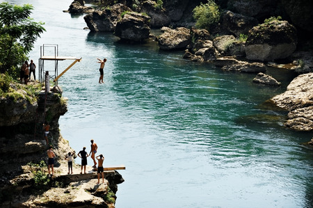 MOSTAR, BOSNIA AND HERZEGOVINA - AUGUST 29: People doing high diving into the Neretva river on...