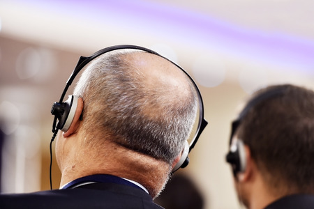 Unrecognizable people using in ear headphones for translation during eventの写真素材