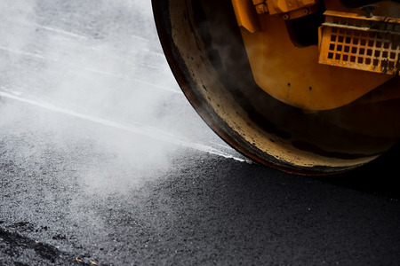 Asphalt paving with a steel wheel roller. Steam coming out from asphalt.の写真素材