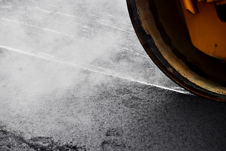Asphalt paving with a steel wheel roller. Steam coming out from asphalt.