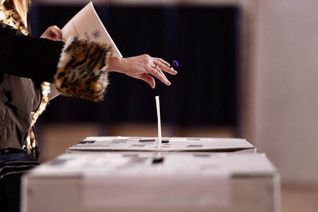 Hand with a stamp casting a vote into the ballot box during electionsの写真素材