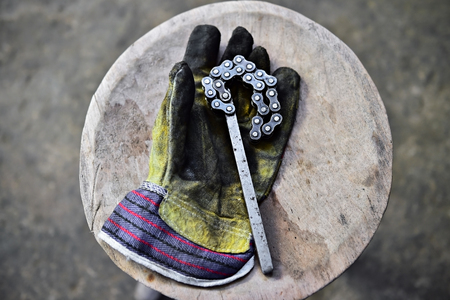Dirty worker's glove holding a tool key on a wooden plank in a workshopの写真素材