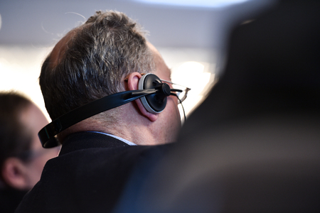 Unrecognizable business people using headphones for translation during eventの写真素材