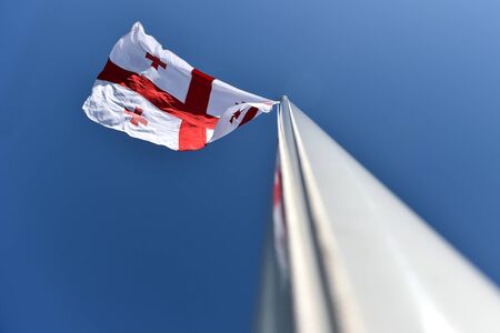 Georgia national flag blown by the wind against a blue skyの写真素材