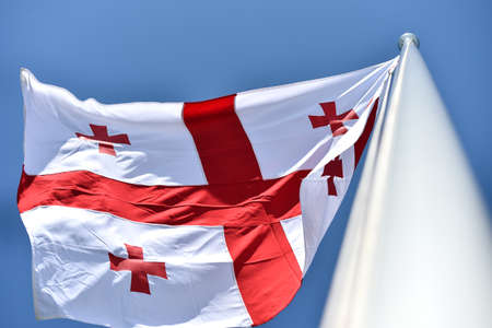 Georgia national flag blown by the wind against a blue skyの写真素材