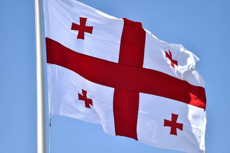 Georgia national flag blown by the wind against a blue skyの写真素材