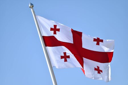 Georgia national flag blown by the wind against a blue skyの写真素材