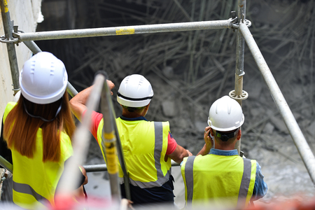Workers inspecting construction works on a scaffold inside construction siteの写真素材