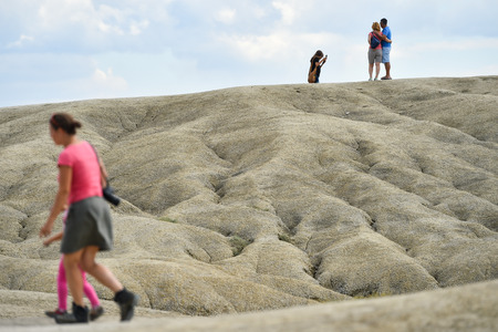 BUZAU, ROMANIA - AUGUST 13, 2016: Groups of tourists visiting mud volcanoes also known as mud domes in summer season.のeditorial素材