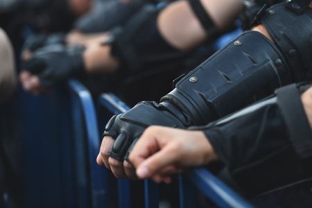 Police officer hands on a security fence during a riotの写真素材