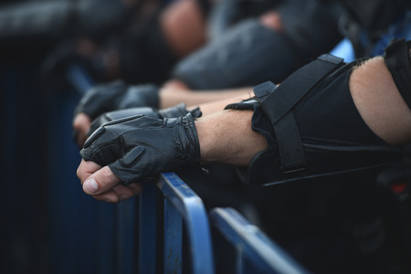 Police officer hands on a security fence during a riotの写真素材