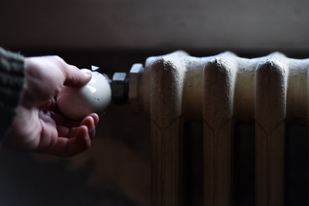 Detail with a hand checking the heat coming from a household radiatorの写真素材