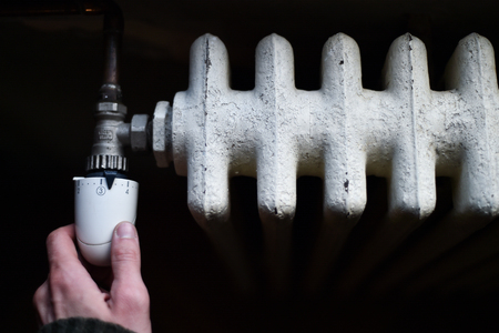 Detail with a hand checking the heat coming from a household radiatorの写真素材