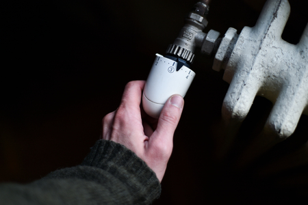 Detail with a hand checking the heat coming from a household radiatorの写真素材